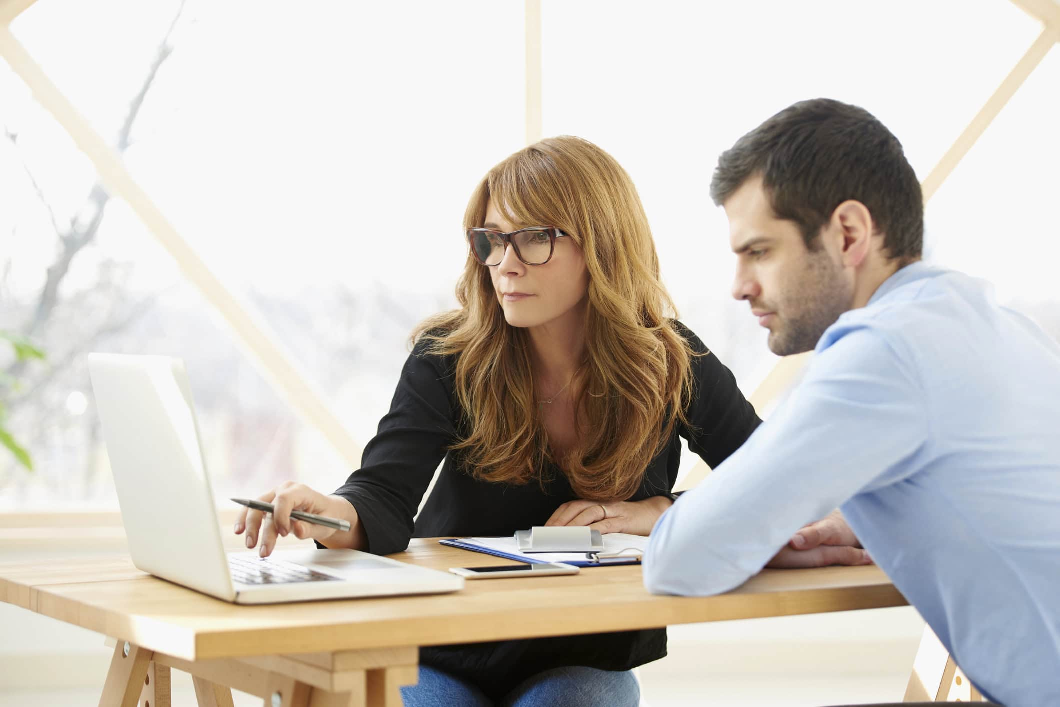 Executive businesswoman giving advice to young professional man Axia Group Bookkeeping, Woman and Man at computer